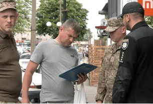 Військові та поліцейський перевіряють документи цивільного на вулиці міста