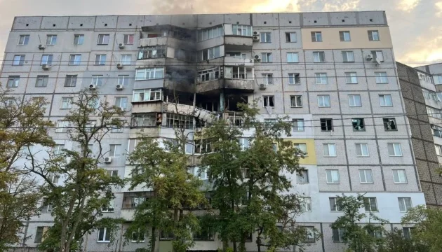 Пошкоджена багатоповерхівка з вигорілими балконами після обстрілу серед дерев